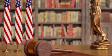 A gavel on a desk with American flags and a library background.
